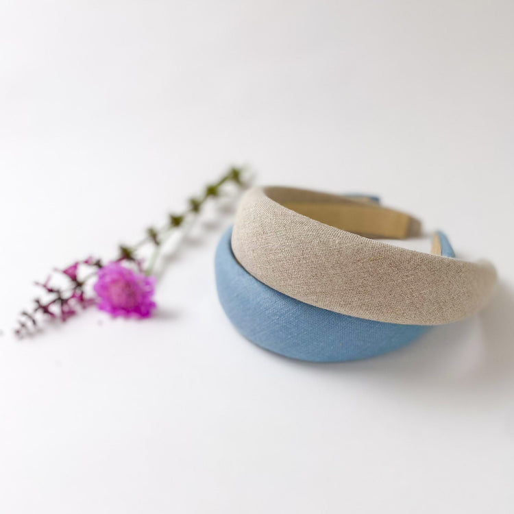 Two Padded hairbands next to a pink flower on a white background